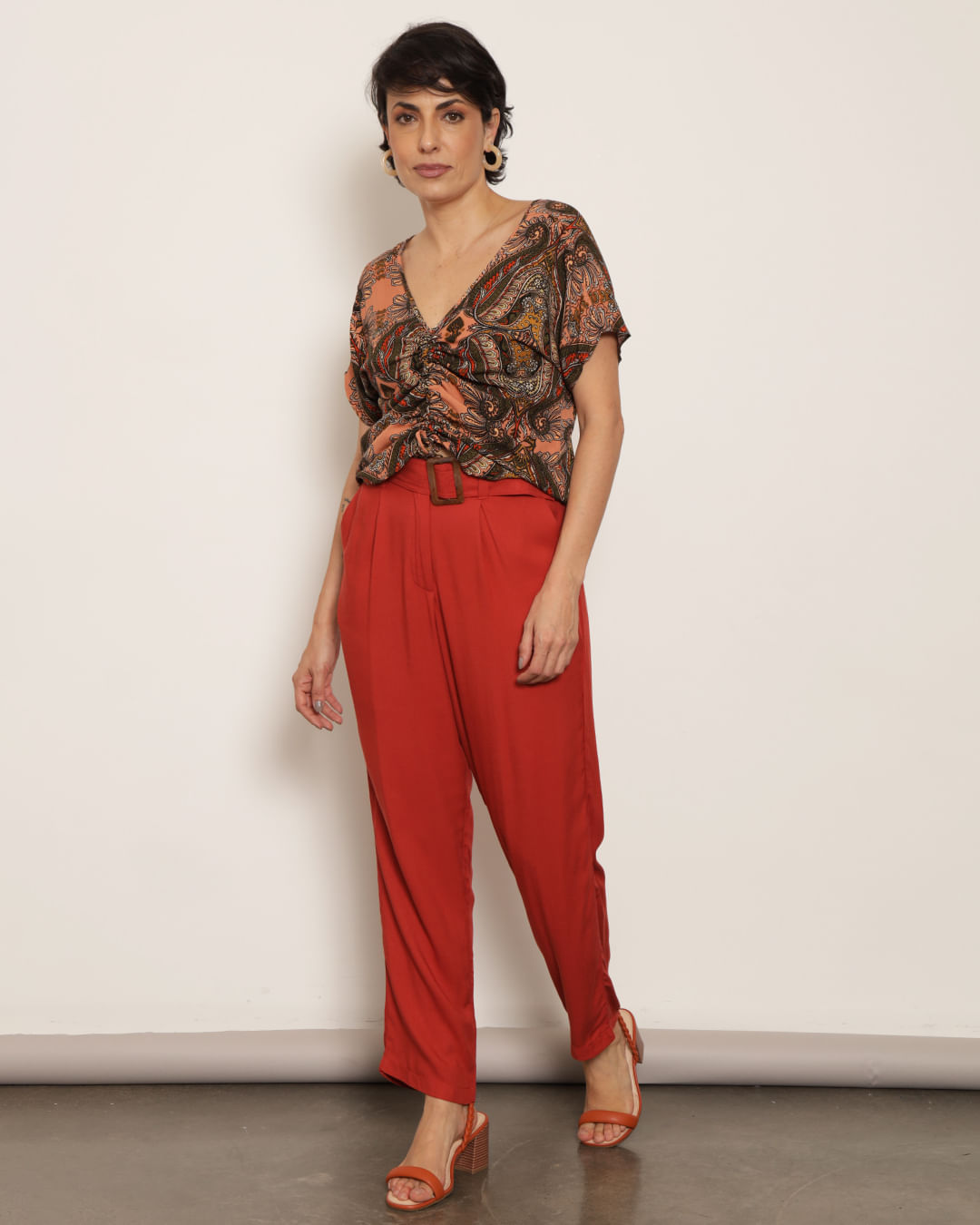Um modelo feminino com um top preto e um cinto vermelho que diz o nome  nas costas.